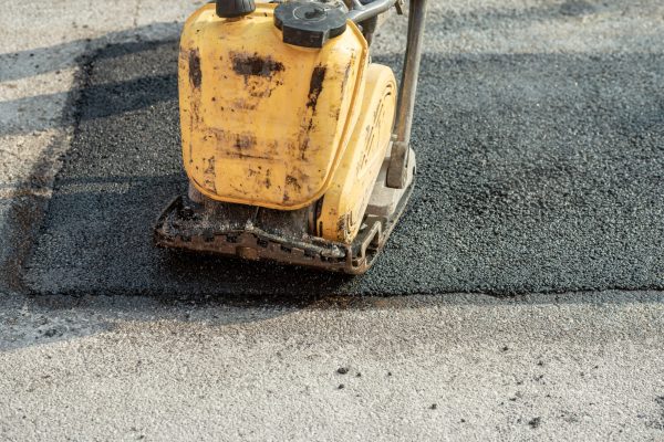 Closeup of a compactor on a new freshly laid asphalt.